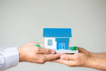 hands holding a blue and white model home